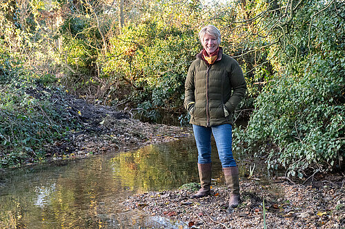 Pippa Heylings stands next to a Cambridgeshire river